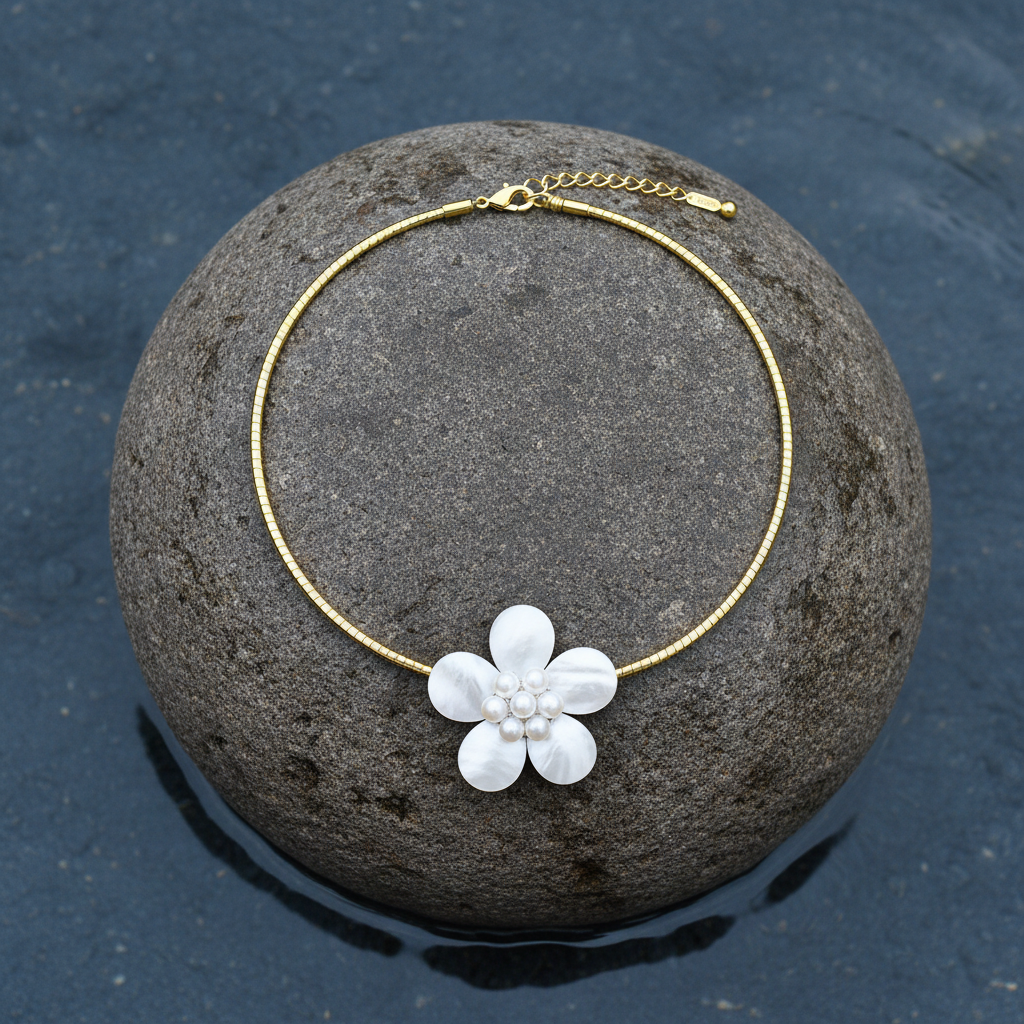 zoetwater parelketting met witte parels, wit parelmoer in de vorm van een bloem en goud edelstaal liggend op steen| Fleury W Gold