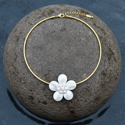 zoetwater parelketting met witte parels, wit parelmoer in de vorm van een bloem en goud edelstaal liggend op steen| Fleury W Gold