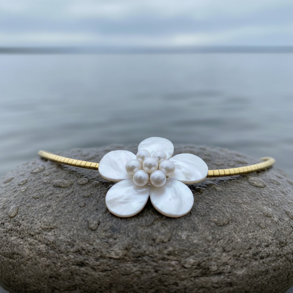 Zoetwater parelketting met witte parels, wit parelmoer in de vorm van een bloem en goud edelstaal liggend op steen met close up | Fleury W Gold