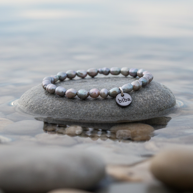 Grijs zoetwater parel armband, elastisch liggend op steen in water | Biba Grey RicePearl