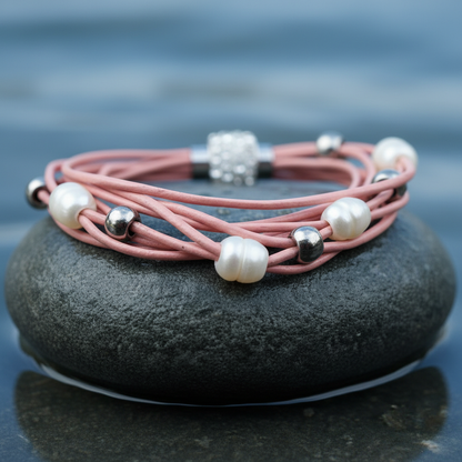 Wit zoetwater parel armband met roze leer en stras steentjes liggend op steen in water | Bling Pearl Pink