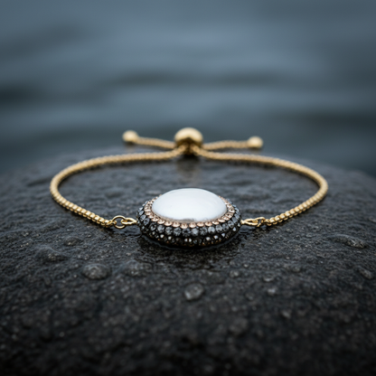Wit zoetwater parel armband met goud edelstaal, stras steentjes en een schuifslotje liggend op steen in water close up | Bright Minimal Gold Coin