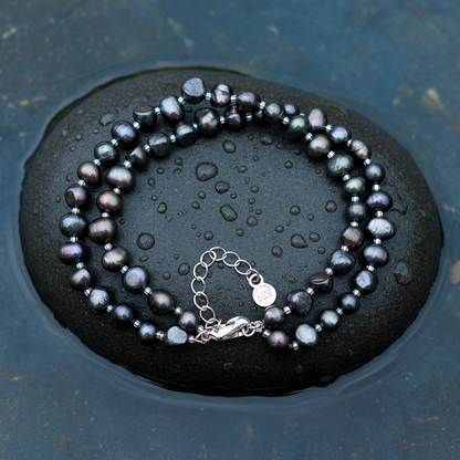 Zoetwater parel armband in 2 rijen met zwart-bruine parels en sterling zilver (925) liggend op steen in water | Danieke