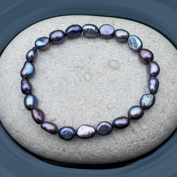 Elastisch parel armband met donkere paars blauwe parels liggend op natte steen | Dessa