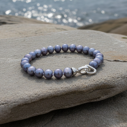 Handgeknoopt zoetwater parel armband met blauw-grijze parels liggend op steen in water | Grizelle
