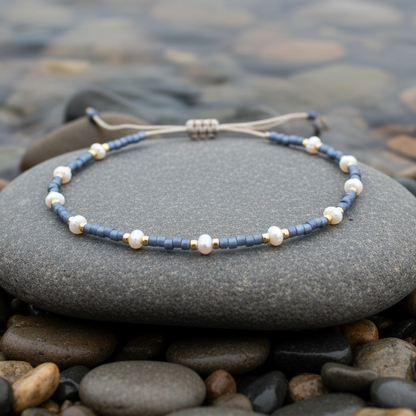 Wit zoetwater parel armband met blauwe en gouden kraaltjes en schuifsluiting liggend op steen in water | Mini Pearl Bead Pursian Blue 