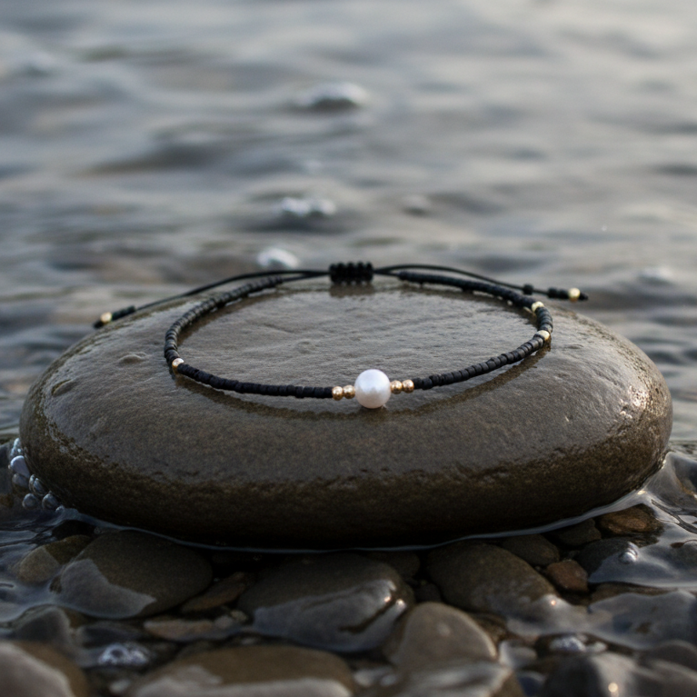Wit zoetwater parelarmband met zwarte kraaltjes liggend op steen in water | Mini Pearl One Black Color