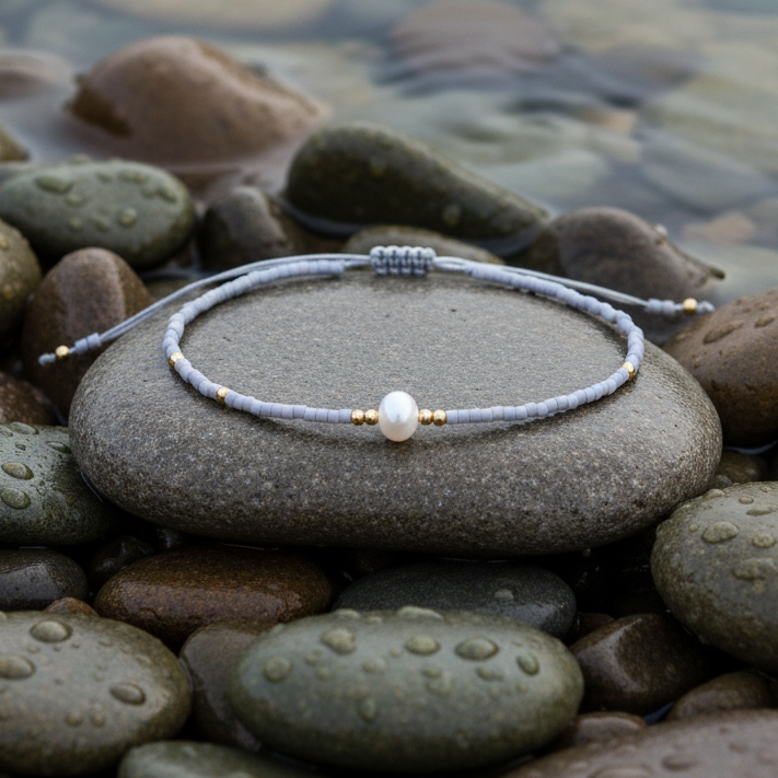 Wit zoetwater parel armbandje met grijze kraaltjes liggend op steen in water | Mini Pearl one Grey Color