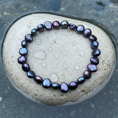 Zoetwater parel armband met blauw paarse parels liggend op steen in water | Pealca