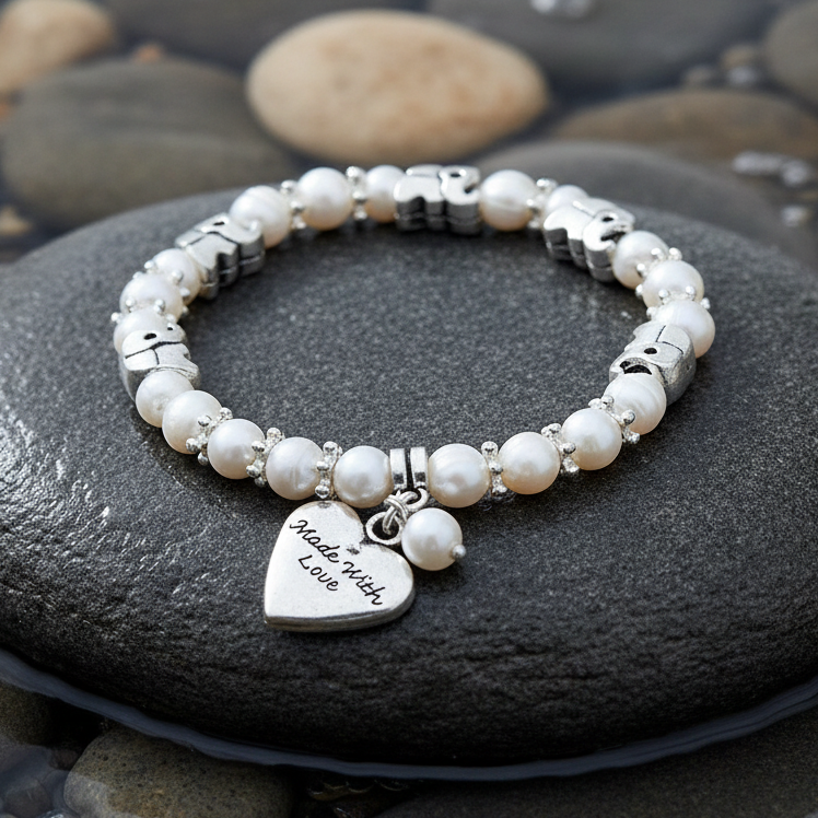 Wit zoetwater parel armband met hartjes bedeltje en zilveren olifantjes liggend op steen | Pearl Elephant Heart