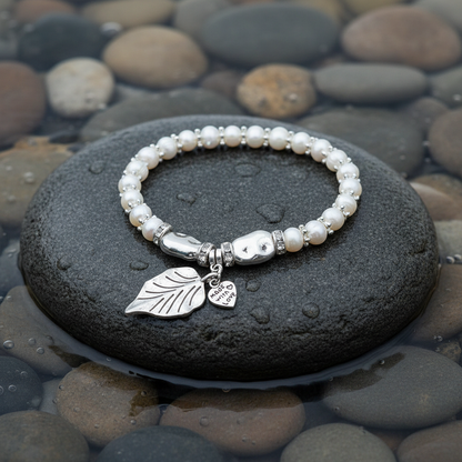Wit zoetwater parel armband met zilveren hartje en blaadje liggend op steen in water, elastisch | Pearl Leaf