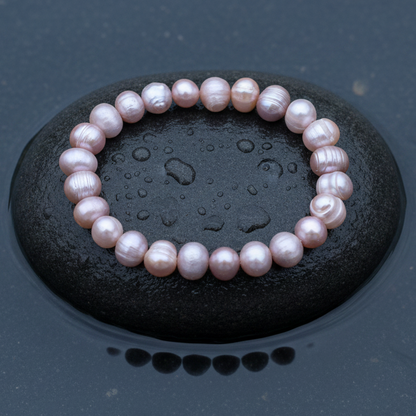 Roze zoetwater parel armband liggend op steen in water, elastisch | Rozemarijn