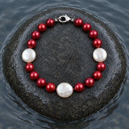 Handgeknoopt zoetwater parel armband met rode en witte parels liggend op steen in water | Ruby