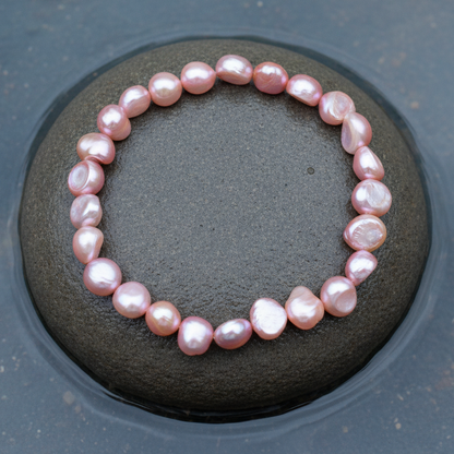 Zalm roze zoetwater parel armband, elastisch liggend op steen in water | Shinny Pearl Pink