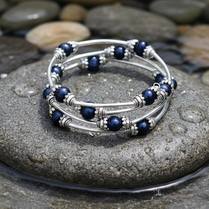 Three Loops Dark Blue Pearl zoetwater parel wikkelarmband close-up op grijze natte steen bij oever