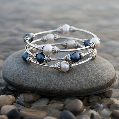 Zoetwater parel wikkelarmband met witte en blauwe parels liggend op steen in water | Three Loops White &amp; Dark Pearl Pearl