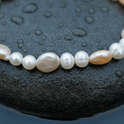 Zoetwater parel armband met wit en zalm kleurige parels liggend op steen in water close up | Zicoin