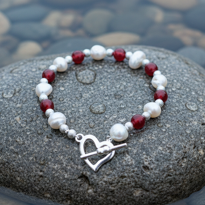 Wit zoetwater parel armband met rode agaat en hartjes slotje liggend op natte steen | Pearl Heart Red Agate