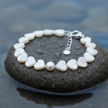 Wit zoetwater parel armband met wit parelmoeren hartjes liggend op steen close up | White Pearl Heart Shell