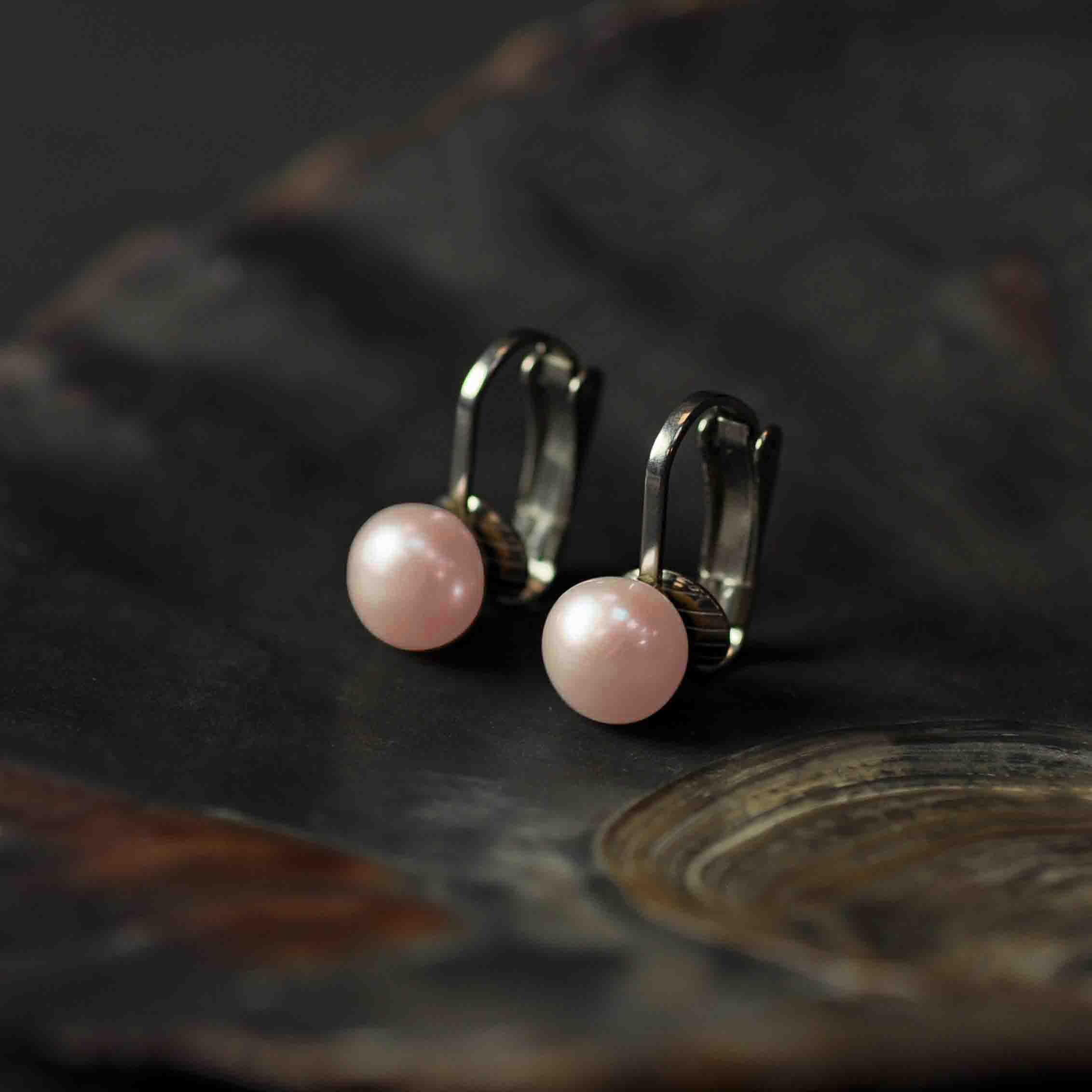 Zoetwater parel clip oorbellen met licht zalm kleurige parels en edelstaal, zijaanzicht liggend in schelp| Clip Pearl Powder