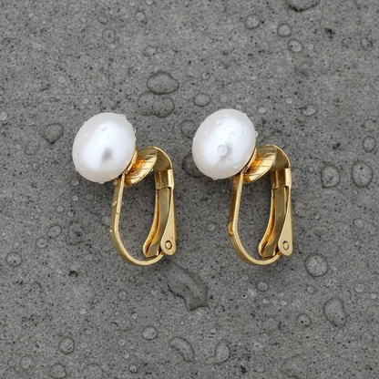 Grote witte zoetwater parel clips oorbellen met goud edelstaal liggend op steen liggend op natte steen | Gold White Clip Pearl 8 mm