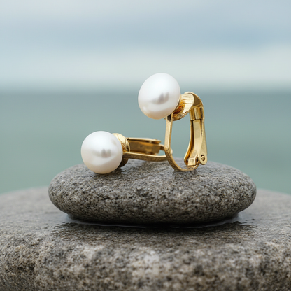 Grote witte zoetwater parel clips oorbellen met goud edelstaal liggend op steen | Gold White Clip Pearl 8 mm