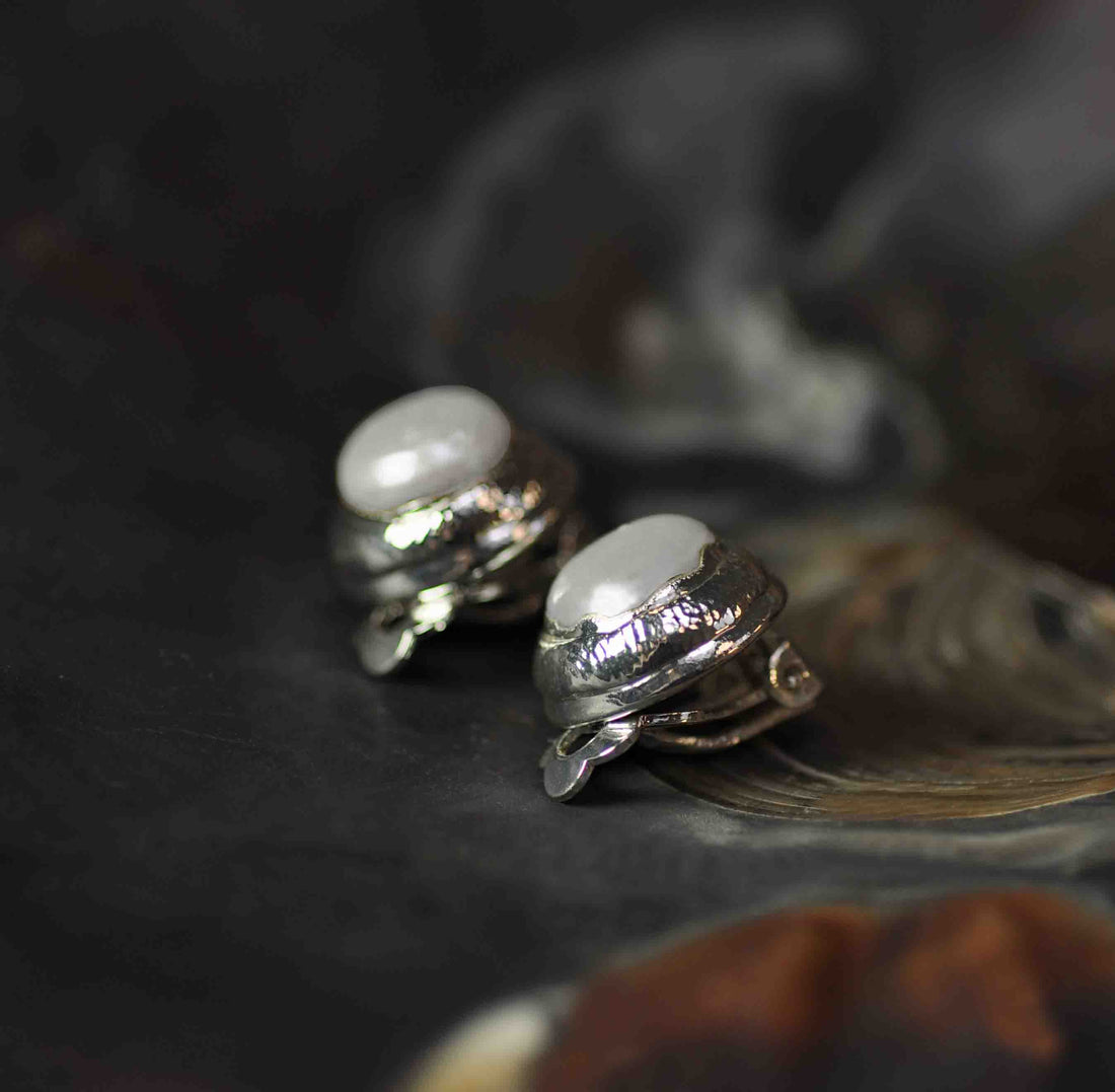 Witte zoetwater parel clips oorbellen met zilveren rand liggend in schelp zijaanzicht | One Silver Clip Pearl