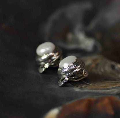 Witte zoetwater parel clips oorbellen met zilveren rand liggend in schelp zijaanzicht | One Silver Clip Pearl