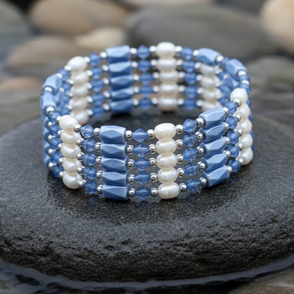 Wit zoetwater parel armband met blauwe magnetiet stenen, opgerold tot armband liggend op steen in water | Wrap Magnetite Blue Pearl