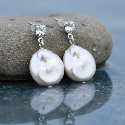 Witte zoetwater parel oorbellen met witte coin parels en stras steentjes in water tegen steen | Bling Colly