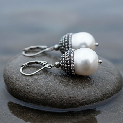 Zoetwater parel oorbellen met witte parel, stras steentjes en sterling zilver 925 liggend op steen | Bling Pearl Big Nuts
