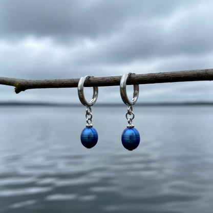 Blauwe zoetwater parel oorbellen hangend aan zilver edelstalen oorring hangend aan takje boven water | Blue Bells