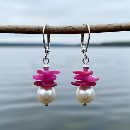 Witte zoetwater parel oorbellen met pink gekleurde stukjes schelp en edelstaal hangend aan takje boven water | Candy