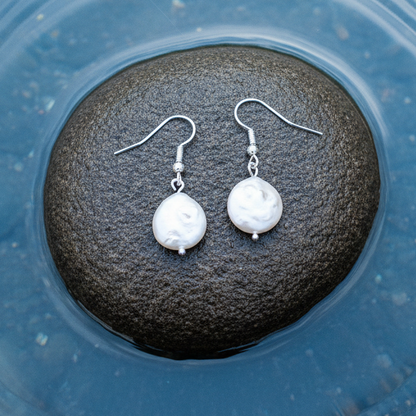 Witte zoetwater parel oorbellen met sterling zilver (925) liggend op steen | Colly White