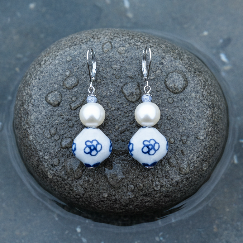 Zoetwater parel oorbellen met witte parel, Delfts blauwe ornament en edelstaal liggend op steen | Hollands Glorie Bloem