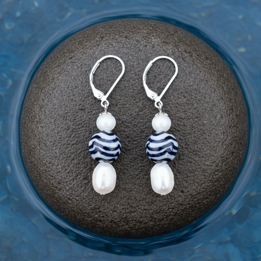 Zoetwater parel oorbellen met witte parel, Delfts blauw ornament en edelstaal liggend op steen | Hollands Glorie Golfje