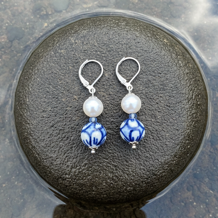 Zoetwater parel oorbellen met witte parels, Delfts blauw ornament en edelstaal liggend op steen | Hollands Glorie Round Flower White