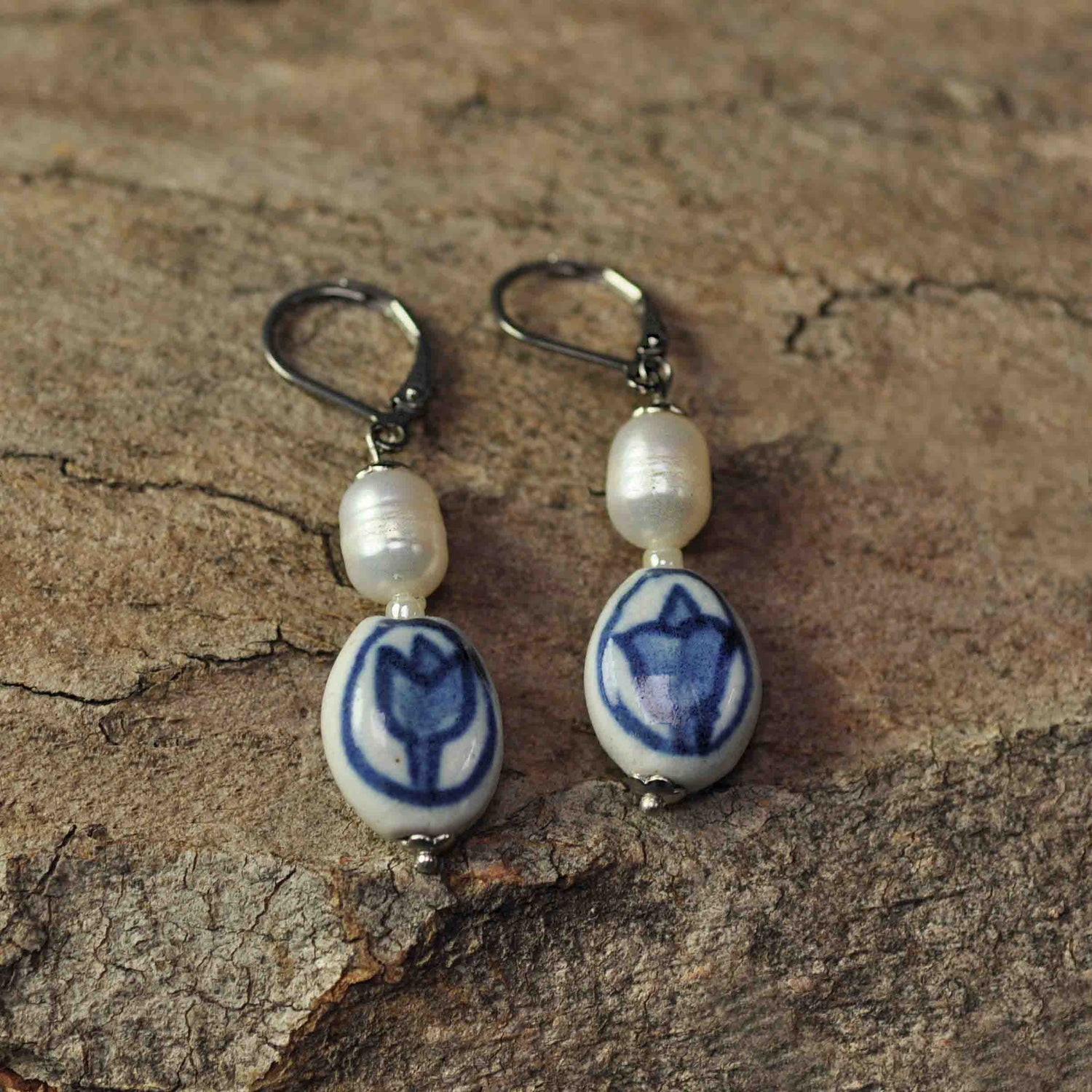 Zoetwater parel oorbellen met witte parels, Delfts blauw ornament en edelstaal liggend op hout | Hollands Glorie Tulp Wit