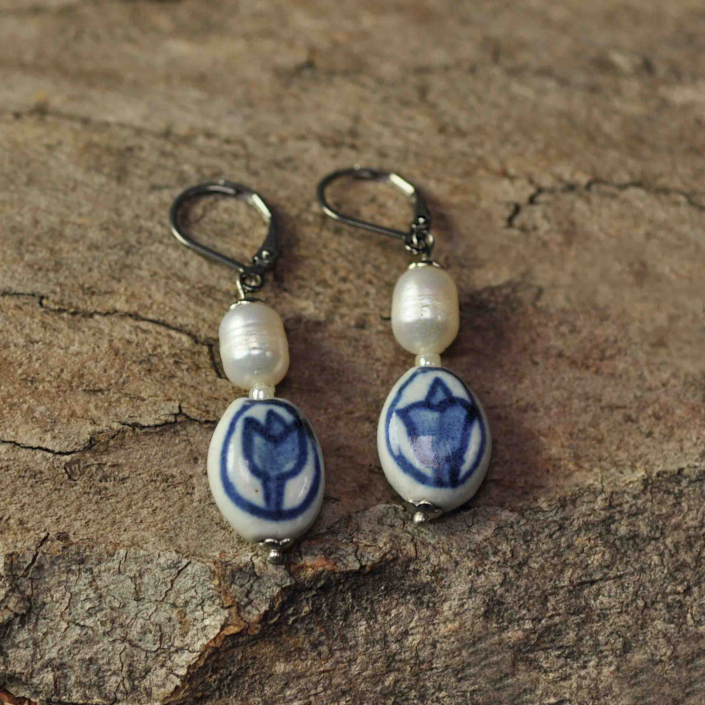 Zoetwater parel oorbellen met witte parels, Delfts blauw ornament en edelstaal liggend op hout | Hollands Glorie Tulp Wit