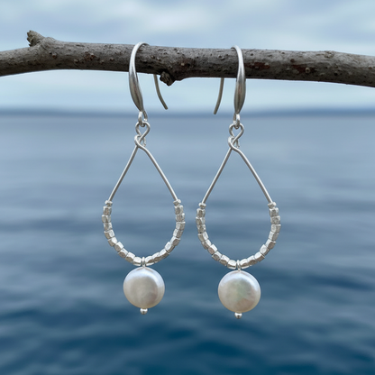 Lange witte zoetwater parel oorbellen met witte coin parel en mat zilver hangend aan takje | Milany Silver