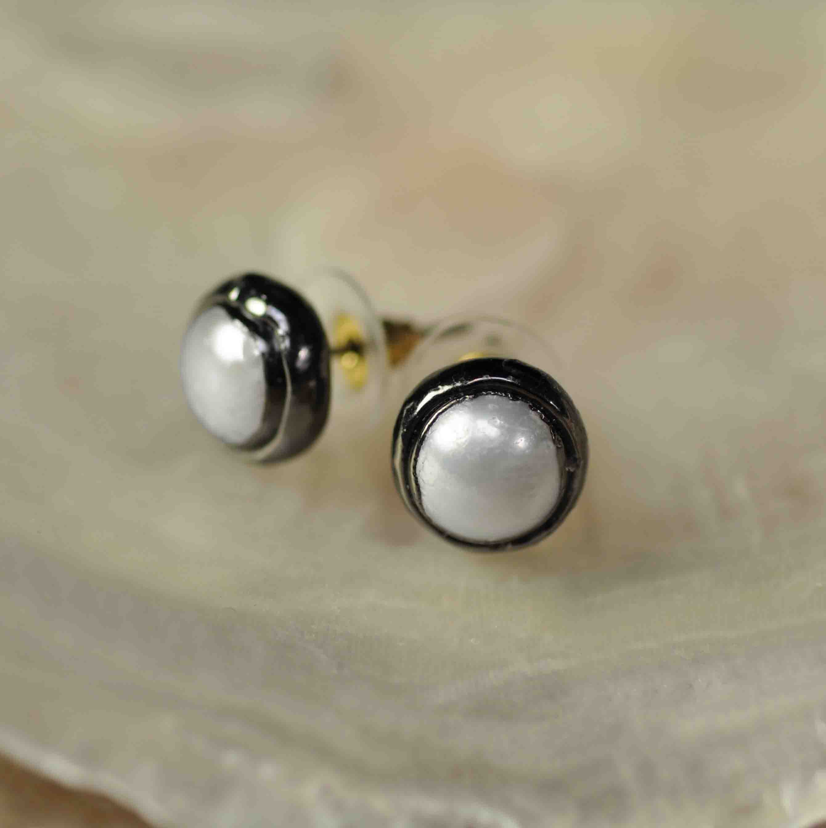 Witte zoetwater parel oorknoppen met zwarte rand liggend in witte schelp| One Metalgun Stud Pearl