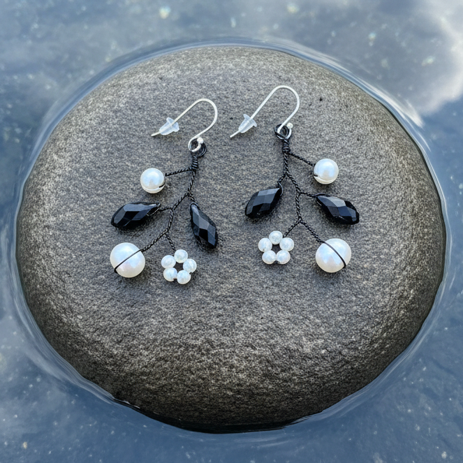 Zoetwater parel oorbellen met witte parels, zwart facet geslepen glas kristallen en sterling zilver (925) liggend op steen  | Pearl Black