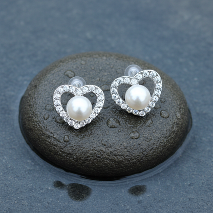 Zoetwater parel oorbellen met witte parel en stras steentjes in hart vorm liggend op steen | Radiant Pearl Heart