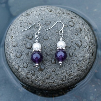 Witte zoetwater parel oorbellen met amethist en sterling zilver (925) liggend op steen in water | Amilia Amethyst