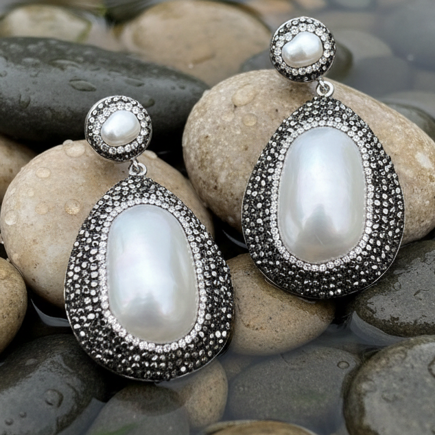 Grote witte zoetwater parel oorbellen met stras steentjes liggend op stenen | Bright Shell Oval