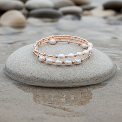 Zoetwater parel wikkel armband met witte parels en rose goud liggend op beige steen in water | Wrap Rose White Pearl