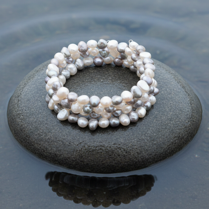 Zoetwater parel armband met witte en grijze parels liggend op natte grijze steen  | Zen White Greyn water