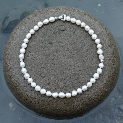 Handgeknoopt parelketting met witte parels liggend op een natte steen | parelketting Big Round pearl