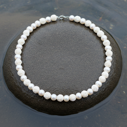 Zoetwater parelketting met witte parels, Chinese knopen en gerhodineerd zilver liggend op steen in water | Chiwa