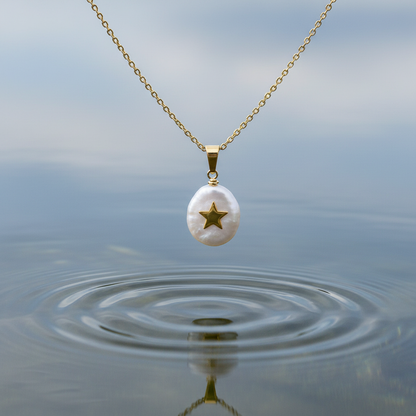 Detail van zoetwater parelketting met witte parel hanger met gouden ster en goud edelstaal hangend boven water | Coin Pearl Golden Star 